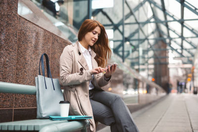 Business woman using smart phone on city street
