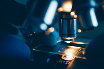 Macro photo showing scientist s gloved hands adjusting optical microscope for analysis